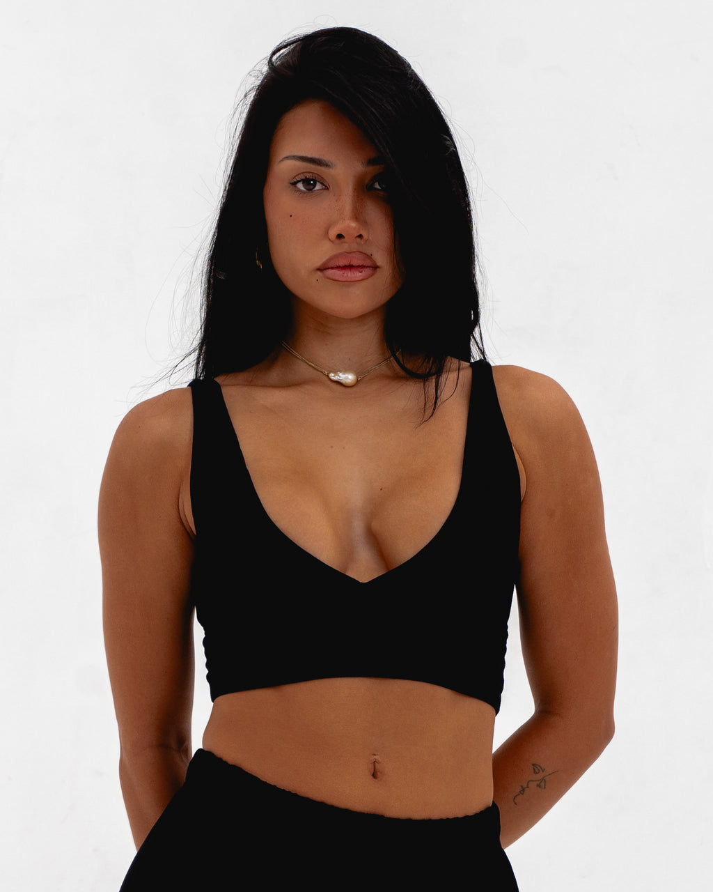 Woman wearing a black sports bra against a white background